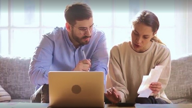 a couple is sitting down in front of a computer